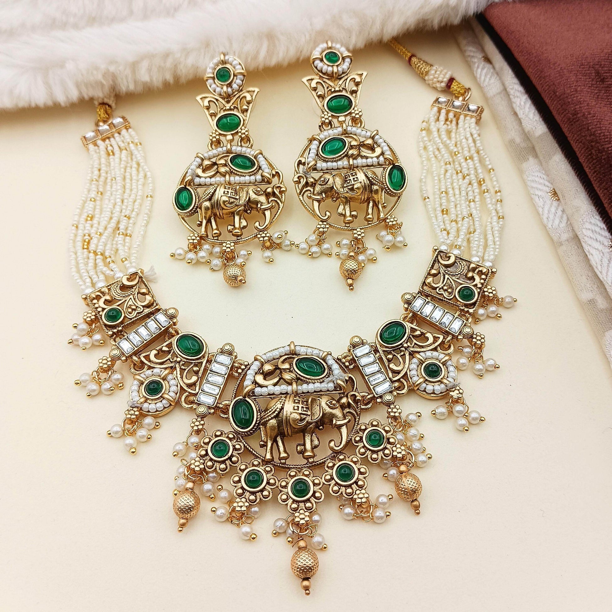 Rajputi elephant design necklace set with green stones and pearl detailing in gold tone