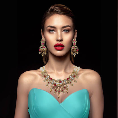 Model wearing Rajputi elephant design necklace set with red stones and matching earrings in gold finish